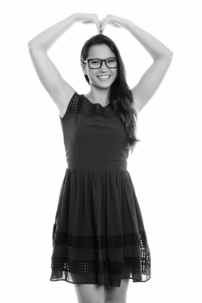 幸せな若い美しい女笑顔とハート記号をジェスチャーしながら立っているのスタジオ撮影 — ストック写真