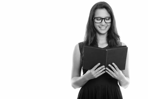 Счастливая молодая красивая женщина улыбается и носит очки во время чтения книги — стоковое фото