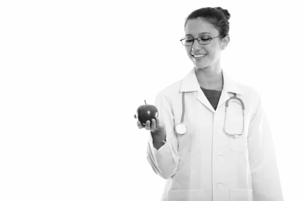 Estúdio tiro de jovem mulher feliz médico sorrindo enquanto segurando e olhando maçã vermelha — Fotografia de Stock