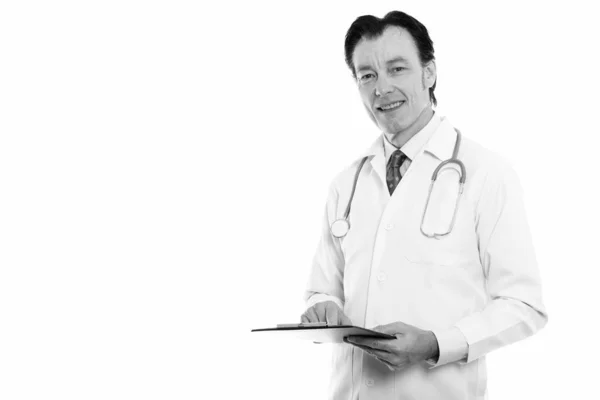 Студійний знімок зрілого щасливого лікаря, який посміхається, тримаючи кишеню — стокове фото