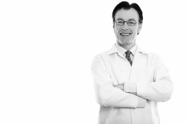 Studioaufnahme eines reifen, glücklichen Mannes Arzt lächelt und trägt eine Brille mit verschränkten Armen — Stockfoto