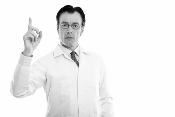 Студийный снимок зрелого красавца-врача в очках, указывающего пальцем — стоковое фото