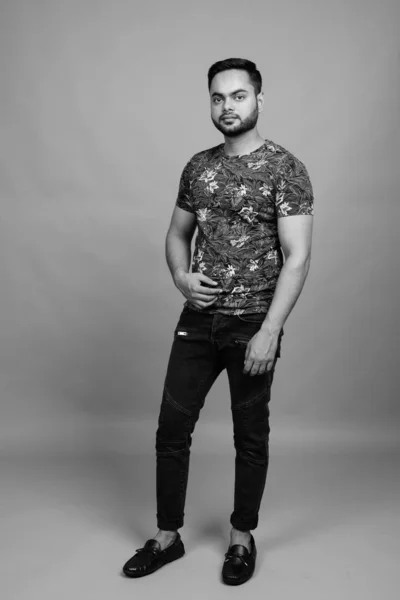 Young bearded Indian man against gray background