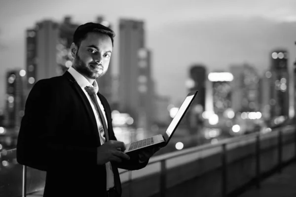 Jonge bebaarde Indiase zakenman tegen het zicht van de stad 's nachts — Stockfoto
