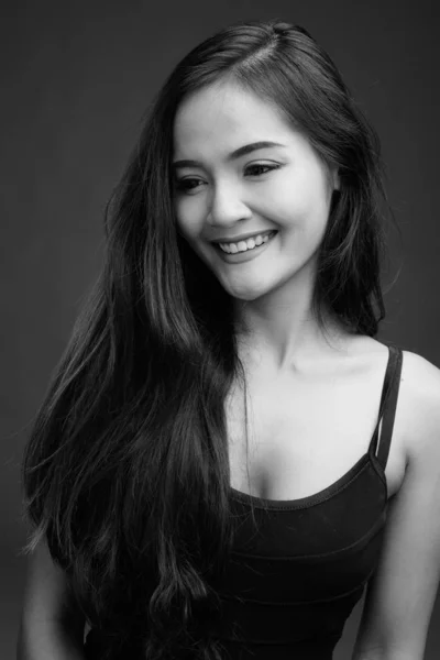 Junge schöne asiatische Frau vor grauem Hintergrund — Stockfoto