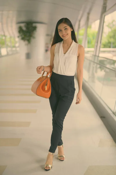 Young beautiful Asian businesswoman hanging out at the footbridge — Stockfoto