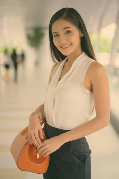 Young beautiful Asian businesswoman hanging out at the footbridge — Stockfoto