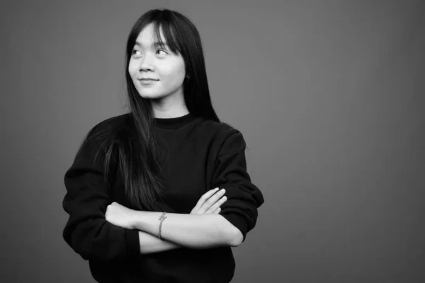 スタジオショットの若いです美しいですアジアの女性身に着けています黒セーターに対してグレー背景で黒と白 — ストック写真