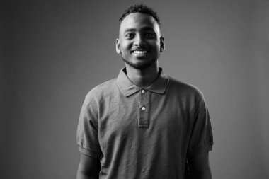 Siyah-beyaz gri arka planda Afrikalı genç bir adamın stüdyo çekimi.