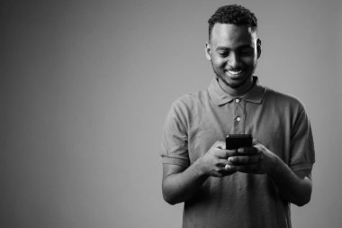 Siyah-beyaz gri arka planda Afrikalı genç bir adamın stüdyo çekimi.