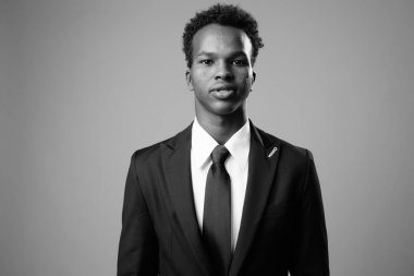 Studio shot of young African businessman against gray background in black and white