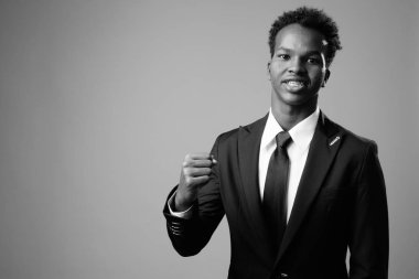 Studio shot of young African businessman against gray background in black and white