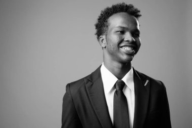 Studio shot of young African businessman against gray background in black and white