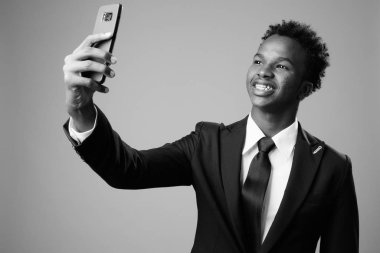 Studio shot of young African businessman against gray background in black and white