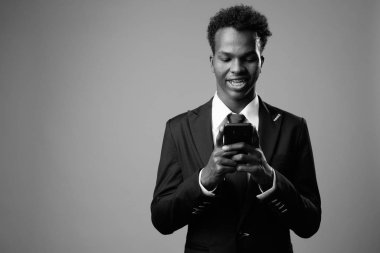Studio shot of young African businessman against gray background in black and white