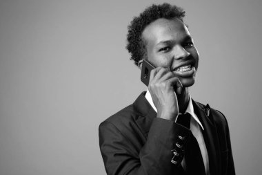 Studio shot of young African businessman against gray background in black and white