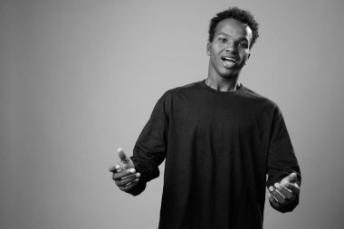 Studio shot of young African man against gray background in black and white