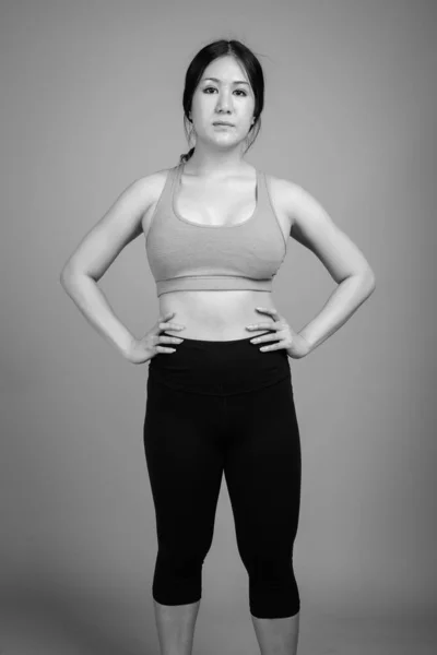 Νεαρή όμορφη Ασιάτισσα γυναίκα έτοιμη για γυμναστήριο με γκρι φόντο — Φωτογραφία Αρχείου