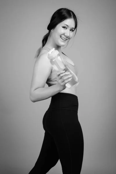 Jeune belle femme asiatique prêt pour la salle de gym sur fond gris — Photo