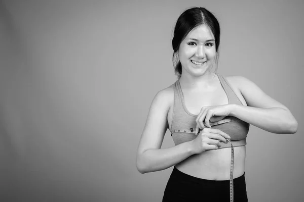 Jovem bela mulher asiática pronta para ginásio contra fundo cinza — Fotografia de Stock