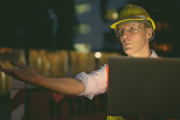 Mature man construction worker at the construction site in the city at night
