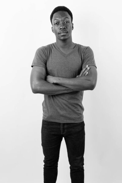 Studio shot of young handsome African man against white background in black and white