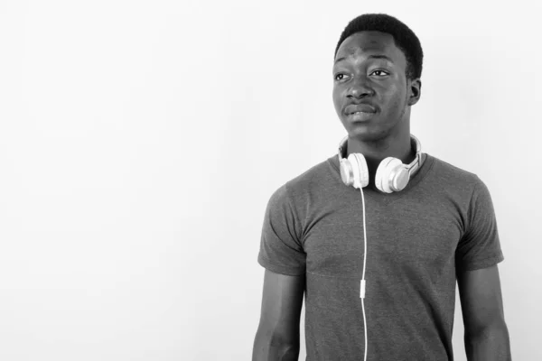 Jovem e bonito homem africano usando fones de ouvido contra fundo branco — Fotografia de Stock