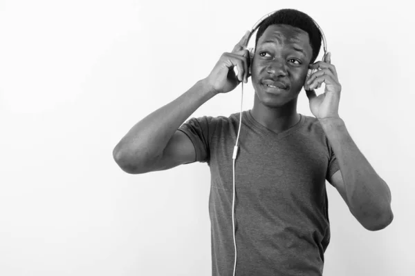 Jovem e bonito homem africano ouvindo música contra fundo branco — Fotografia de Stock