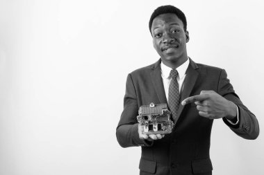 Genç yakışıklı Afrikalı işadamı beyaz arka planda ev heykelciği tutuyor