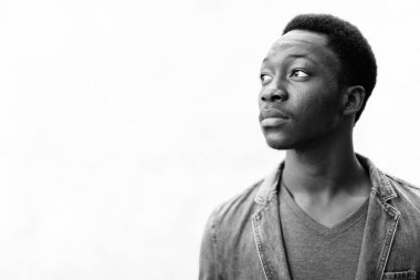 Dışarıdaki beton duvara karşı kot ceket giyen yakışıklı Afrikalı genç adam.