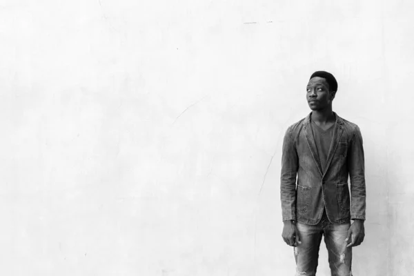 Junger gutaussehender afrikanischer Mann trägt Jeansjacke gegen Betonwand im Freien — Stockfoto