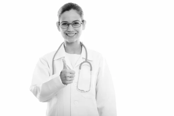 Studio shot de jeune femme heureuse médecin souriant tout en donnant pouce vers le haut — Photo