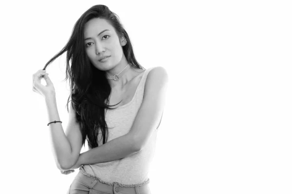 Studio shot of young beautiful Asian woman touching her hair — Stock Photo, Image