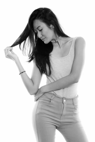 Studioaufnahme einer jungen schönen asiatischen Frau, die sich beim Anblick ihrer Haare berührt — Stockfoto