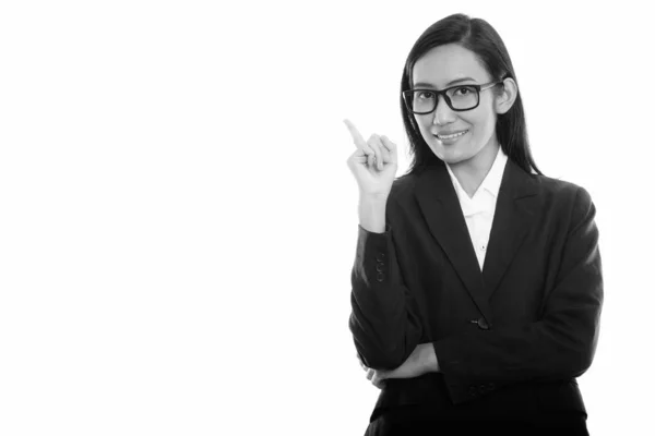 Studio shot de joven feliz mujer de negocios asiática sonriendo mientras señala con el dedo hacia arriba —  Fotos de Stock