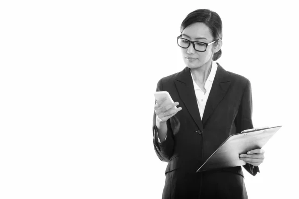 Студийный снимок молодой азиатской предпринимательницы, держащей планшет, используя мобильный телефон — стоковое фото