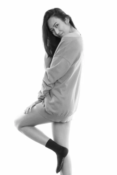 Studio shot de joven hermosa mujer asiática posando mientras mira hacia atrás — Foto de Stock