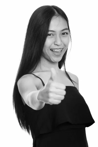 Stüdyo çekim gülümseyen ve başparmak pes etmek genç mutlu Asyalı genç kız — Stok fotoğraf