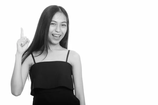 Stúdió felvétel fiatal boldog ázsiai tizenéves lány mosolyogva, miközben felfelé mutató ujj — Stock Fotó