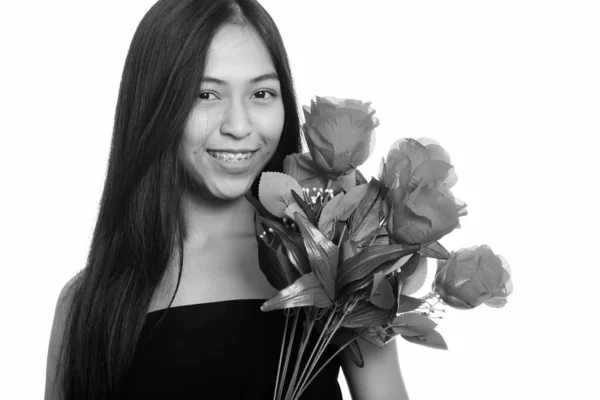 Молодий щасливі Азіатська Дівчинка-підліток посміхаючись утримуючи червоних троянд — стокове фото