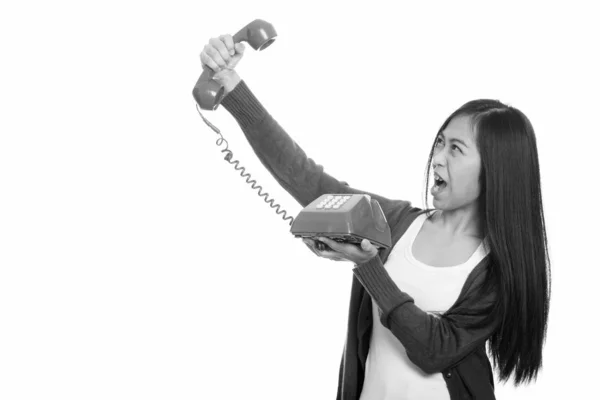 Studio colpo di giovane asiatico adolescente ragazza holding vecchio telefono looking arrabbiato — Foto Stock