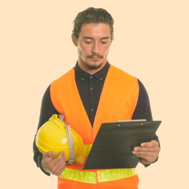 Genç yakışıklı adam inşaat işçisi kask tutarak ve beyaz arka plan karşı izole Pano bakarak, stüdyo vurdu