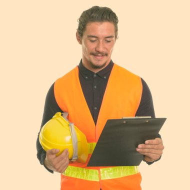 Genç mutlu adam inşaat işçisi kask holding ve beyaz arka plan karşı izole Pano bakarak gülen, stüdyo vurdu