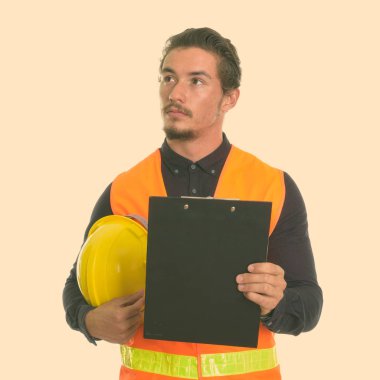 Genç yakışıklı adam inşaat işçisi kask ve beyaz arka plan karşı izole Pano tutarken düşünme stüdyo çekim