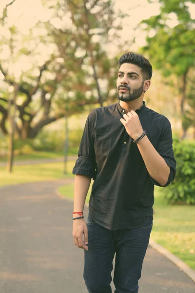 Portrait of young handsome Indian man in the park outdoors