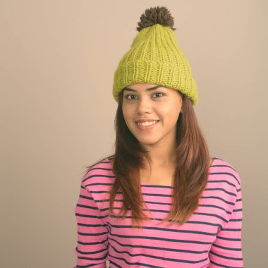 Gri bir arka plana dayanır örme şapka giyen genç güzel Hint kadın stüdyo çekim