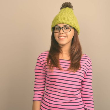 Gri bir arka plana dayanır örme şapka giyen genç güzel Hint kadın stüdyo çekim