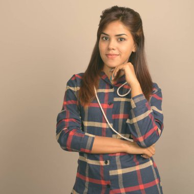 Stüdyo çekim giyen genç güzel Hintli kadın gömlek gri arka plan kontrol