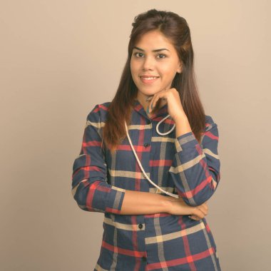 Stüdyo çekim giyen genç güzel Hintli kadın gömlek gri arka plan kontrol