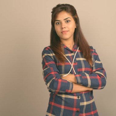 Stüdyo çekim giyen genç güzel Hintli kadın gömlek gri arka plan kontrol